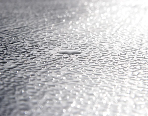 Dew drops on metal surface in sunbeams — Stock Photo, Image