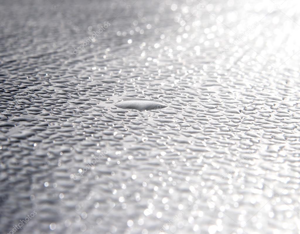 Dew drops on metal surface in sunbeams