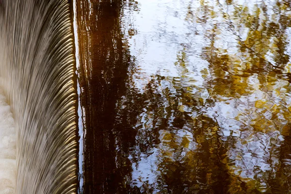 Fallande vatten och reflektion av trädgrenar och sky — Stockfoto