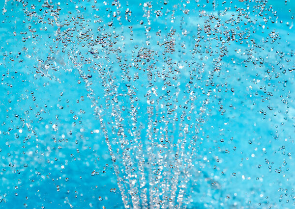 Water spray fountain on turquoise background