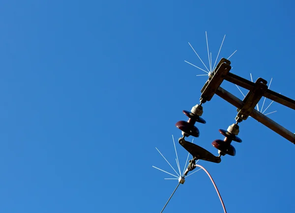 High-voltage electrical insulator of electric line against blue — Stock Photo, Image