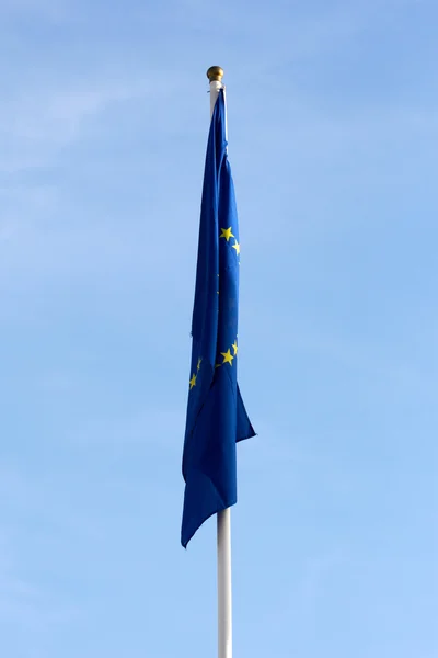 Kulhání vlajka Evropské unie proti modré obloze — Stock fotografie