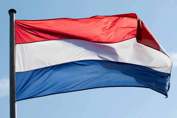 Голландский флаг против неба в солнечном свете — стоковое фото