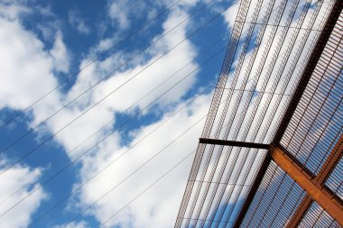 Mavi gökyüzü karşı güvenlik çit ve yüksek gerilim kabloları