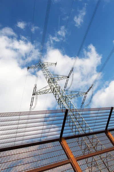 Electricity pylon and barrier fence against the blue sky — Stock Photo, Image