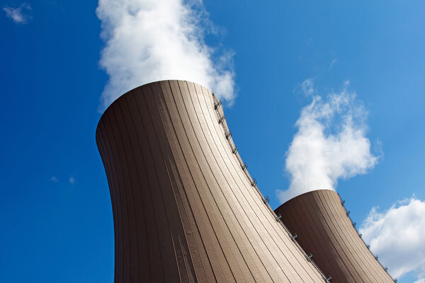 Охлаждающие башни атомной электростанции против неба и облаков

