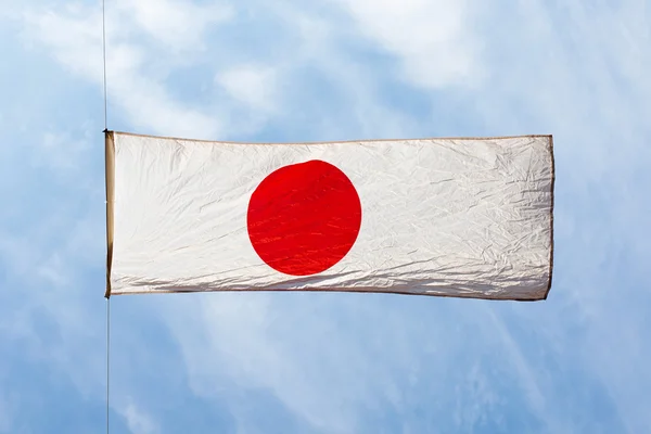 Japanse vlag in de wind tegen de blauwe hemel — Stockfoto