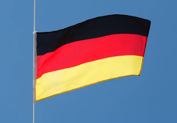 Duitse vlag in de wind tegen blauwe hemel — Stockfoto