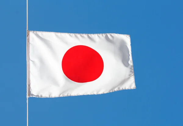 Japanska flaggan i vind mot himlen — Stockfoto