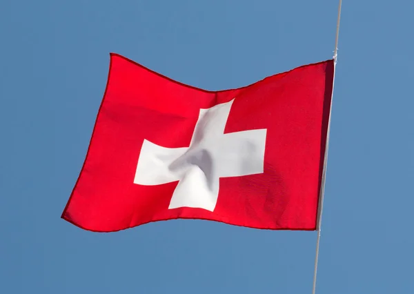 Swiss vlag in de wind tegen de hemel — Stockfoto