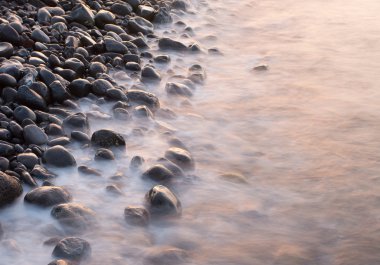 Deniz kıyısında yükselen güneş ışığında