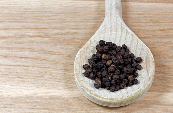 Black pepper on wooden spoon — Stock Photo, Image