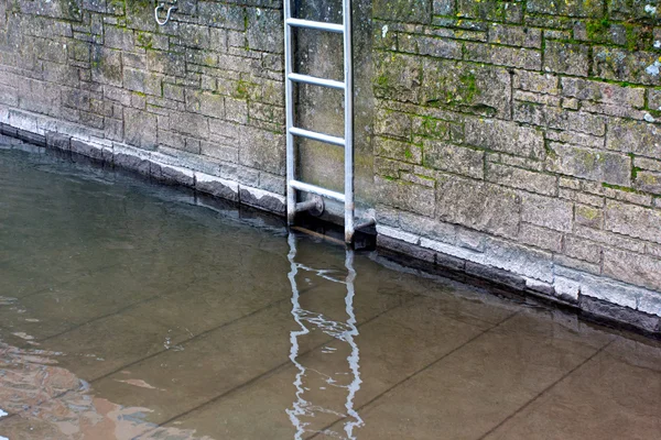 Металлическая лестница на каменной стене у реки — стоковое фото