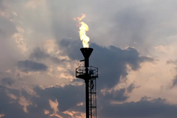 Öl brennende Fackel gegen den Abendhimmel — Stockfoto