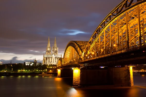 Eisenbahnbrücke am Rhein gegen Kölner Dom in der Nacht — Stockfoto