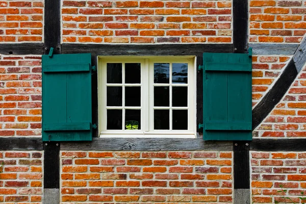 Venster met shutters in bakstenen muur van halve vakwerkhuis — Stockfoto