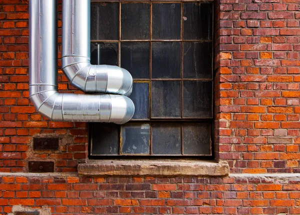 Steel pipes outside the window of  brick building — Stock Photo, Image