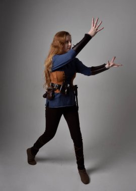 Ortaçağ Viking ilham verici bir kostüm giyen, uzun bir kılıç taşıyan, stüdyo arka planında duran kızıl saçlı kadının tam boy portresi..