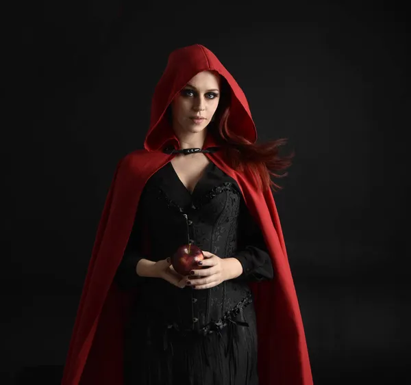 Bruxa assustadora de halloween com olhos vermelhos em um manto preto em um  ambiente sombrio