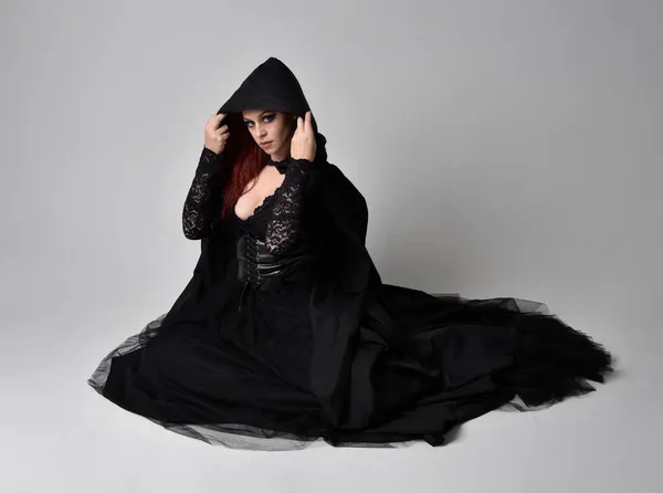 Полноразмерный Портрет Темноволосой Женщины Черном Костюме Ведьмы Сидящей Студийном Фоне — стоковое фото