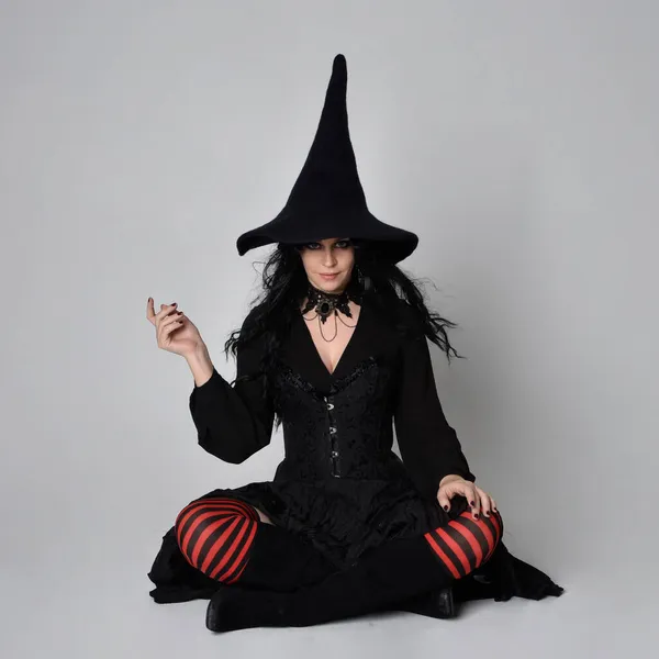 全长的黑发女子肖像 身穿黑色维多利亚式的女巫服装 手部有手势动作 背景在工作室 — 图库照片