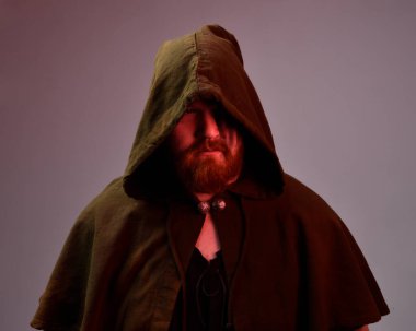  Ortaçağ Viking 'i giyen kızıl saçlı adamın portresi koyu gölgeli ve yüz boyalı fantezi pelerin kostümünden esinlenmiştir. Silüet ışıklandırmalı karanlık bir stüdyonun arka planına karşı.