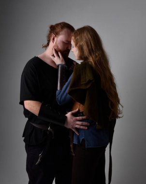 Kızıl saçlı bir çiftin tam boy portresi, ortaçağ Viking 'i giymiş bir kadın ve erkek ilham verici fantezi kostümleri, romantik pozlar, beyaz stüdyo arka planında izole edilmiş..