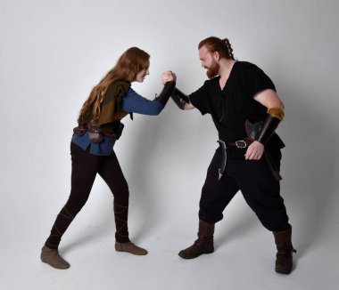 Kızıl saçlı bir çiftin tam boy portresi, ortaçağ Viking 'i giyen bir adam ve kadın ilham verici fantezi kostümleri, ayakta duruş, beyaz stüdyo arka planında izole edilmiş..