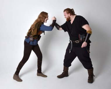 Kızıl saçlı bir çiftin tam boy portresi, ortaçağ Viking 'i giyen bir adam ve kadın ilham verici fantezi kostümleri, ayakta duruş, beyaz stüdyo arka planında izole edilmiş..