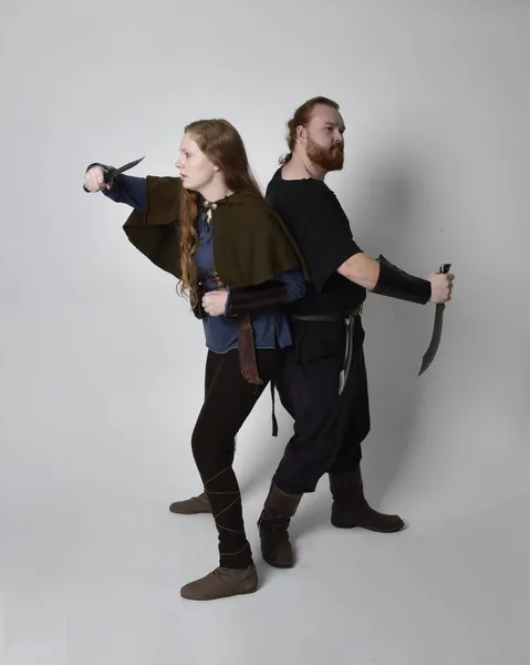 赤髪のカップルの完全な長さの肖像画 男性と女性は 中世のバイキングからインスピレーションを受けたファンタジー衣装を身に着けています 剣の武器を保持する立ちポーズ 白いスタジオの背景に隔離されました — ストック写真