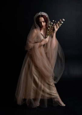 Full length  portrait of red haired  girl wearing a creamy fantasy gown like a fairy goddess costume.  standing  pose with elegant gestural movement , isolated on dark studio background. clipart