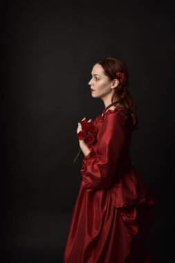  Kızıl saçlı güzel bir kadın modelin portresi Viktorya dönemi kırmızı balo elbisesi giyiyor. Huysuz, karanlık bir geçmişi olan poz vermek..