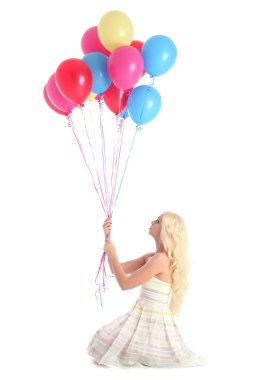 Parti elbisesi giymiş, elinde renkli balonlar tutan sarışın kızın tam boy portresi. Beyaz stüdyo arka planında izole edilmiş.