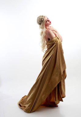  Yunan tanrıçası Toga elbisesi giymiş, stüdyo arka planında zarif hareketlerle poz veren güzel bir kadın modelin tam boy portresi..