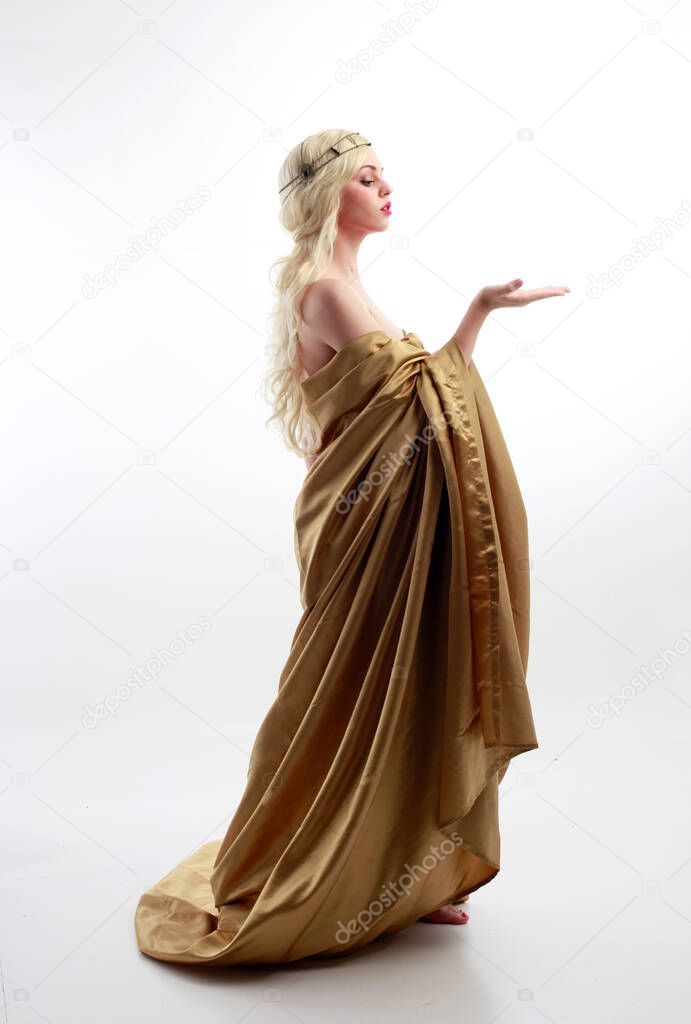  Full length portrait of pretty female model wearing  grecian goddess  toga gown, posing with elegant gestural movements on a studio background.