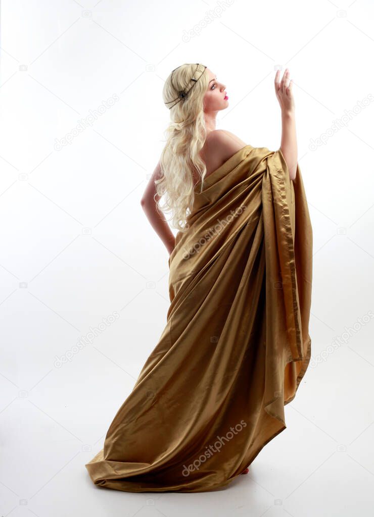  Full length portrait of pretty female model wearing  grecian goddess  toga gown, posing with elegant gestural movements on a studio background.