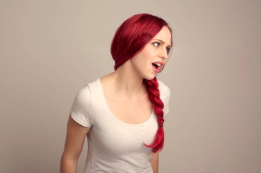 Örgülü kızıl saçlı güzel bir kadın modelin portresi stüdyo arkaplanındaki yüz ifadesi üzerinden duygularını ifade ediyor..