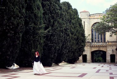 Kızıl saçlı güzel gotik bir elbise giyen, romantik kale taşı mimarisi geçmişi olan, uzun boylu bir kadın portresi..