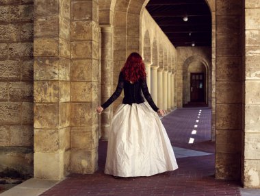 Kızıl saçlı güzel gotik bir elbise giyen, romantik kale taşı mimarisi geçmişi olan, uzun boylu bir kadın portresi..