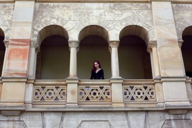 Kızıl saçlı güzel gotik bir elbise giyen, romantik kale taşı mimarisi geçmişi olan, uzun boylu bir kadın portresi..
