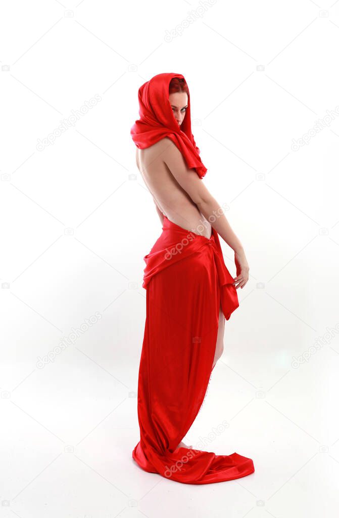 Full length portrait of red haired woman wearing a  beautiful sexy silk gown costume, standing pose with creative arm gestures, isolated on white studio background.