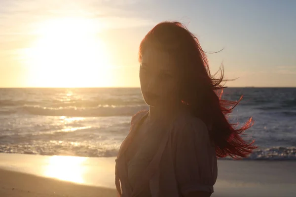 Full length portrait of  red haired woman wearing  torn shipwrecked clothing. Standing  pose with gestural hands at  rocky ocean beach landscape background.