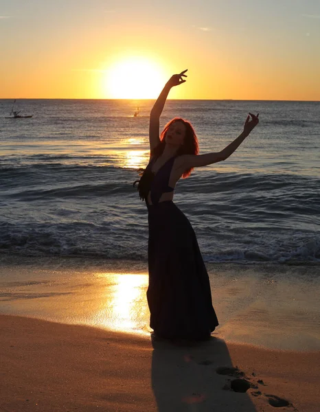 红头发女人穿着雅致长袍的全长肖像 在夕阳西下的海滨景观背景下 手牵手站立着 — 图库照片