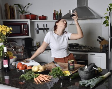  Sıradan kıyafetler ve önlük giyen kızıl saçlı bir kızın portresi. Gerçek ev mutfağında sağlıklı sebze yemeği hazırlıyor.