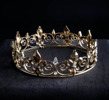 close up of a  beautiful real golden crown, isolated on dark black studio background.