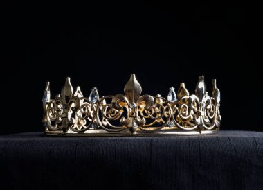 close up of a  beautiful real golden crown, isolated on dark black studio background.