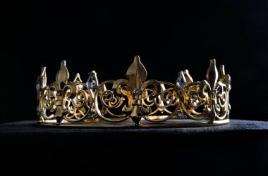 close up of a  beautiful real golden crown, isolated on dark black studio background.