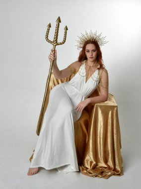 portrait of beautiful red head woman wearing long flowing fantasy toga gown with angelic  golden halo crown on studio background clipart