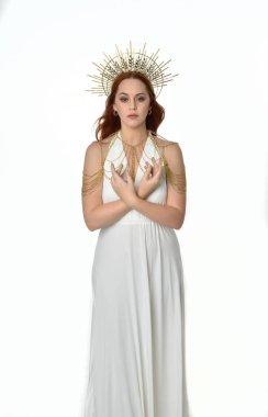 portrait of beautiful red head woman wearing long flowing fantasy toga gown with angelic  golden halo crown on studio background clipart