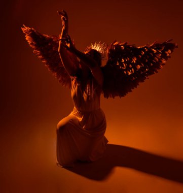portrait of beautiful red head woman wearing long flowing fantasy toga gown with angelic  golden halo crown on studio background